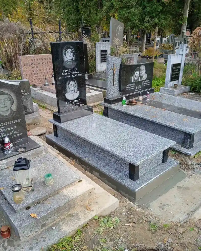 Одинарний гранітний пам'ятник із сірого та чорного каменю з двома гравірованими портретами.