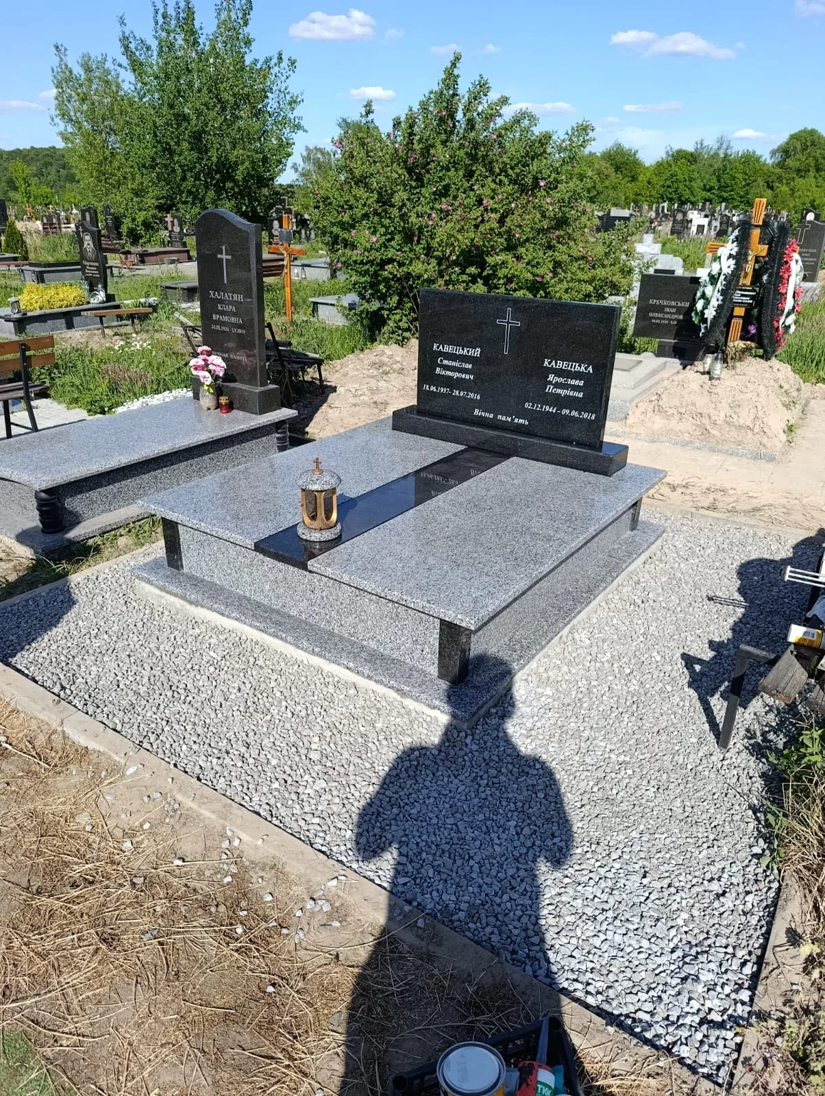 Сірий гранітний подвійний пам'ятник з чорними елементами, встановлений майстернею Пам'ятники Пилипчук. Вигляд на меморіал з гравійною доріжкою, ліхтарем.